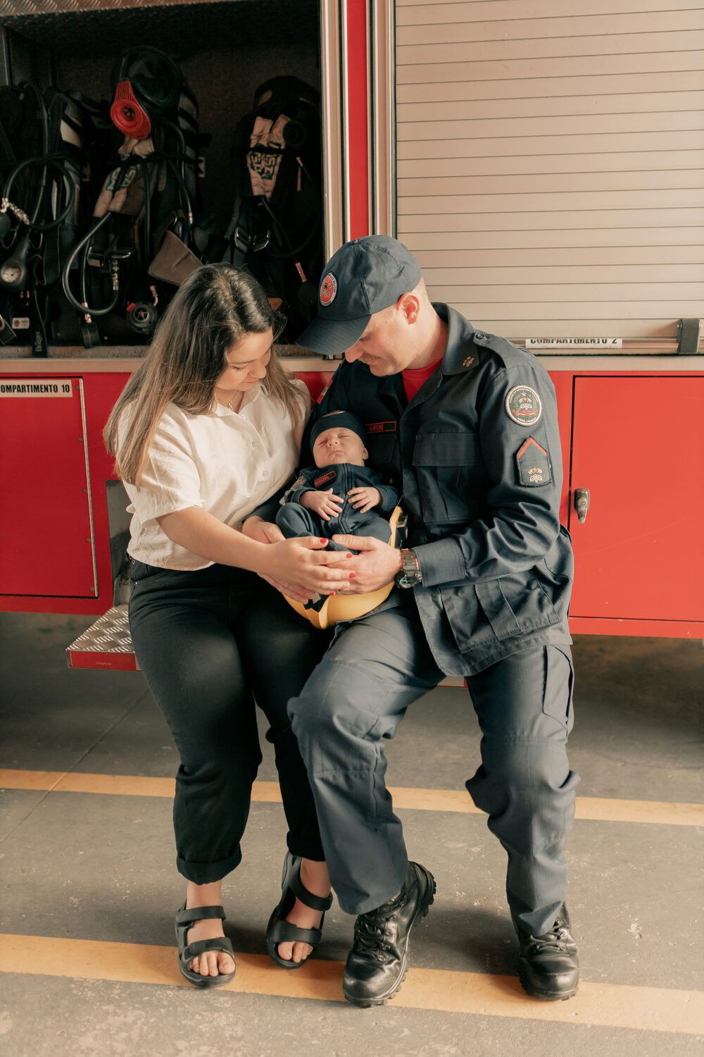 A first responder holding his newborn with his wife at the fire station